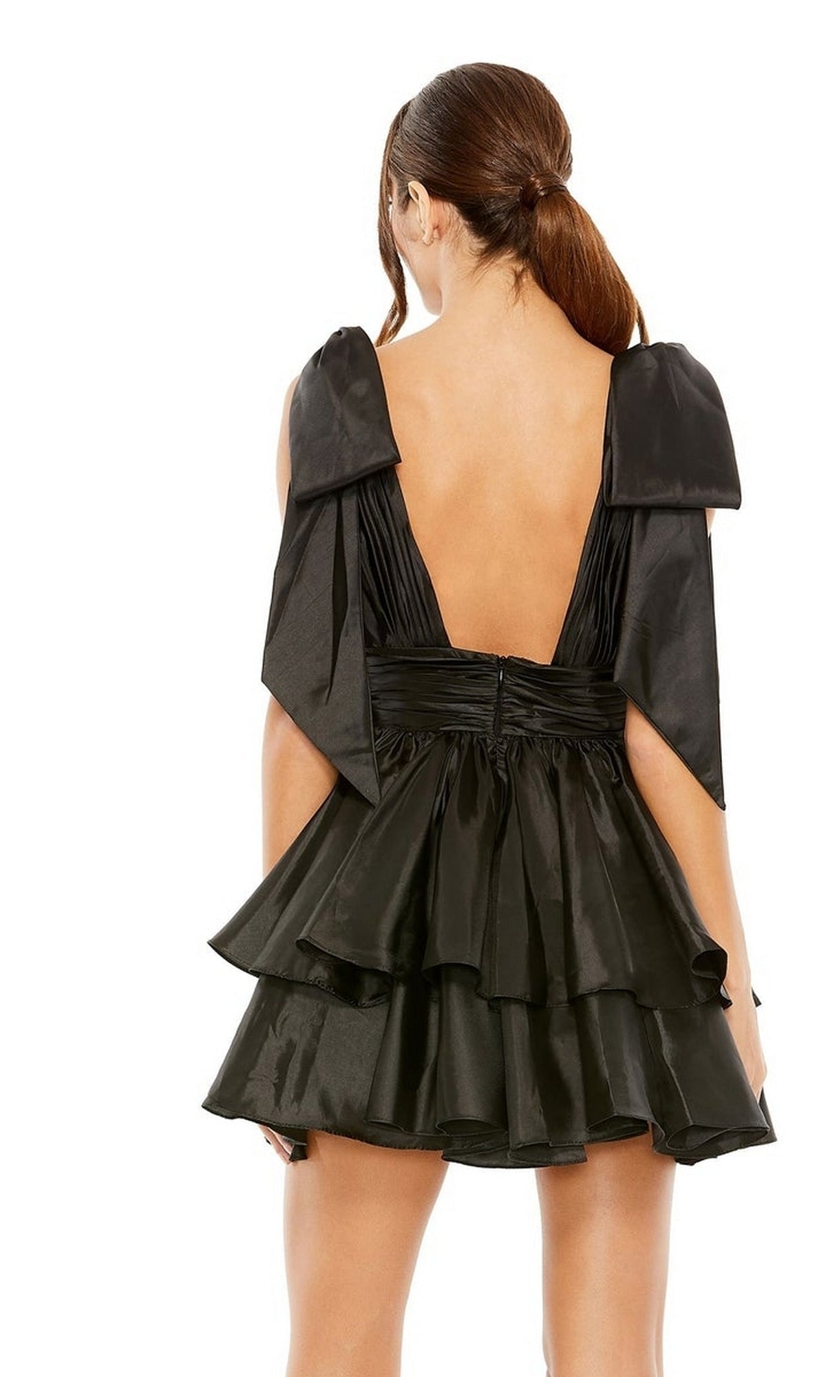 A woman with a low ponytail faces away, wearing the Bow Short Ruffled Hoco Dress: Mac Duggal 11657, featuring an open back and large bow-like shoulder details.